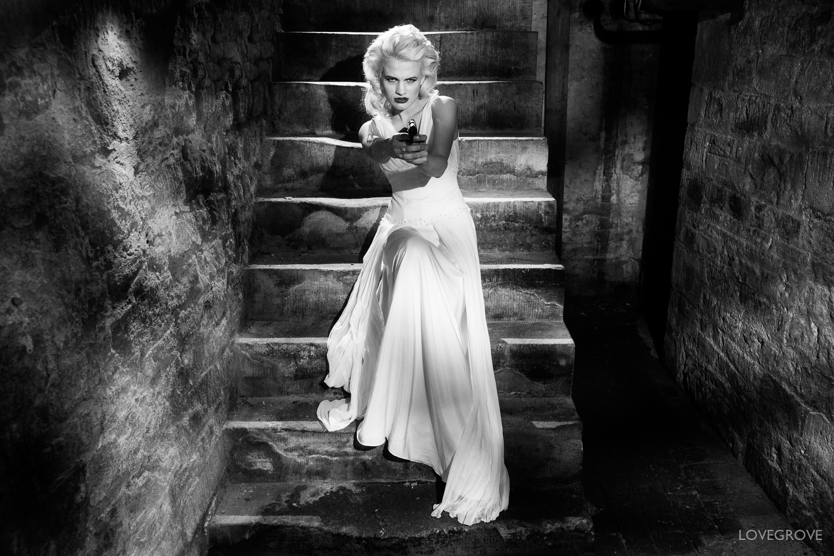 Chloe-Jasmine Whichello on the cellar stairs with a Walther PPK hand gun.