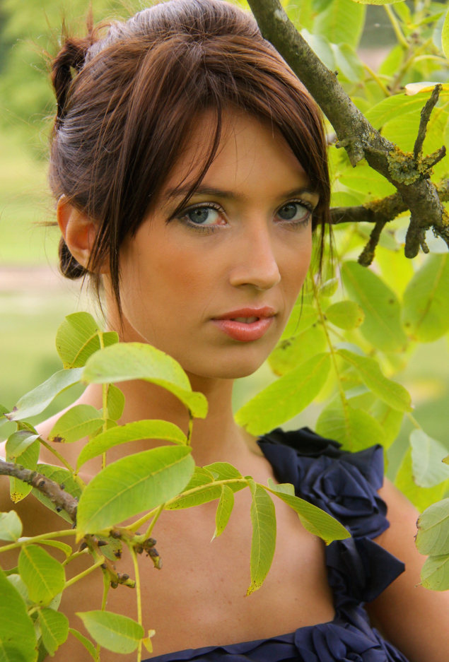 Young female model stood in-between tree foliage